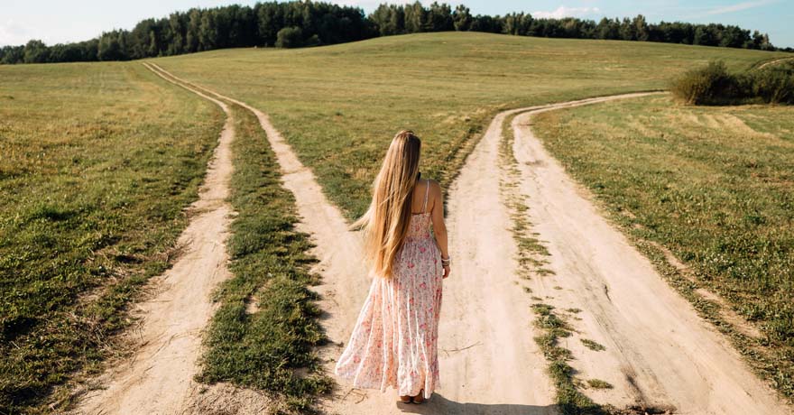 Woman standing at fork in the road in nature